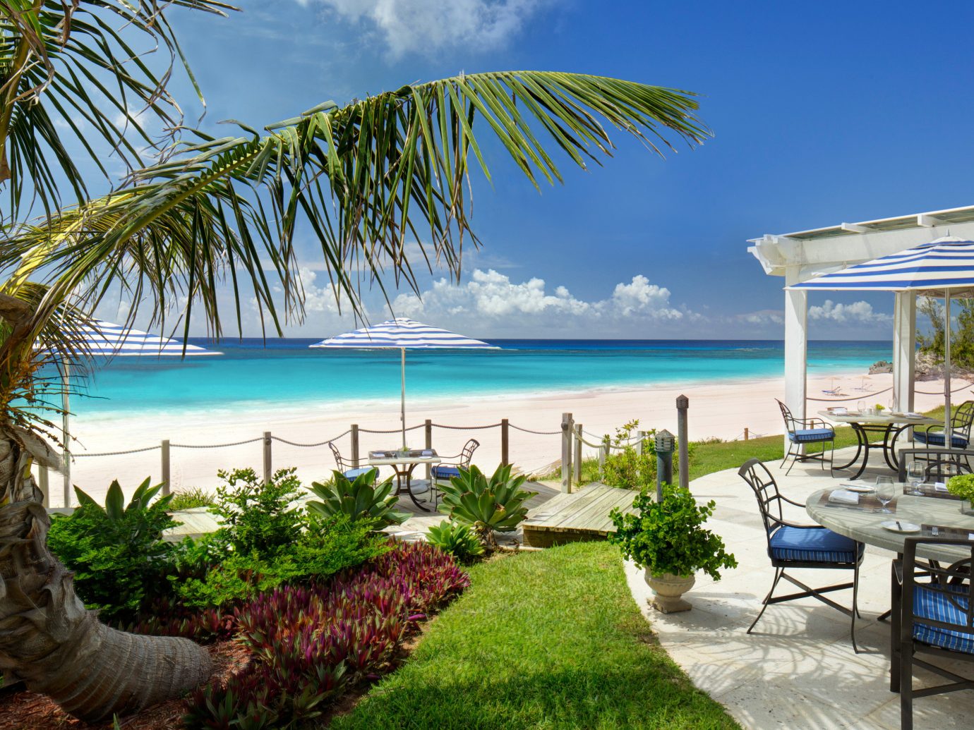 Beach Beachfront Hotels Island Lounge Outdoors Trip Ideas Tropical Waterfront outdoor water tree sky palm umbrella chair Ocean property leisure caribbean vacation swimming pool plant Pool lawn Resort arecales estate real estate tropics bay Villa condominium Sea overlooking shore lined sandy furniture shade