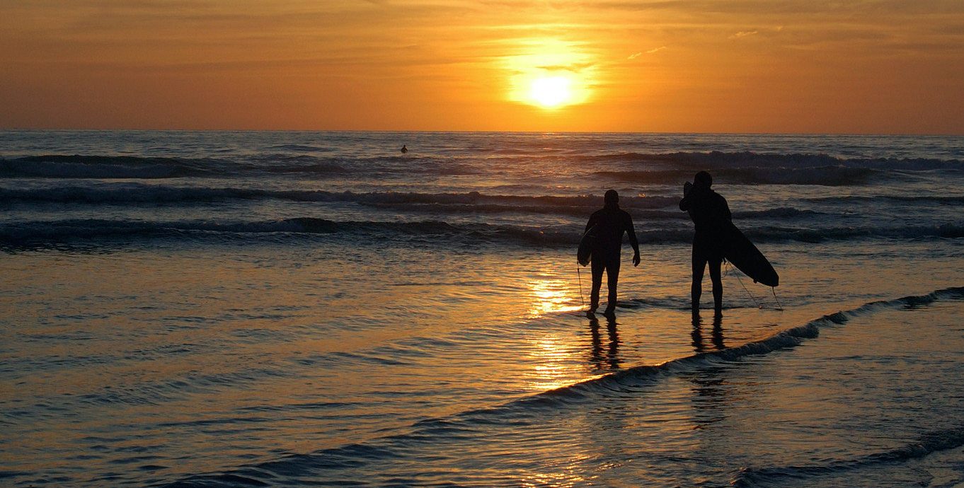 Surfers At Pacific Ocean In San Diego At Sunset