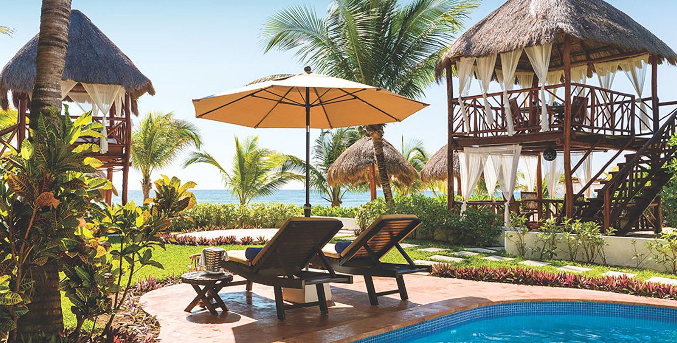 Hotels outdoor tree umbrella chair property Resort building leisure estate swimming pool real estate outdoor structure cottage lawn gazebo home backyard vacation Villa hacienda landscaping outdoor furniture lined set shade furniture several