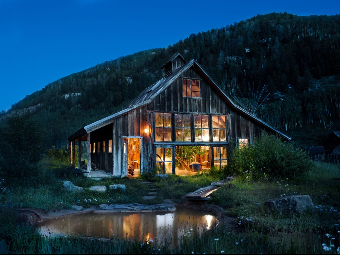 Boutique Hotels Fall Travel Hotels Outdoors + Adventure sky outdoor Nature reflection home building cottage house mountain hut log cabin evening rural area real estate mountain range landscape Winter farmhouse tree barn night computer wallpaper water estate hillside