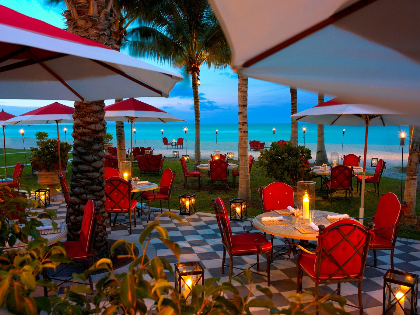 Beachfront Courtyard Dining Drink Eat Honeymoon Hotels Patio Romance Scenic views Terrace Waterfront umbrella chair outdoor Resort restaurant lawn vacation meal colorful set furniture several