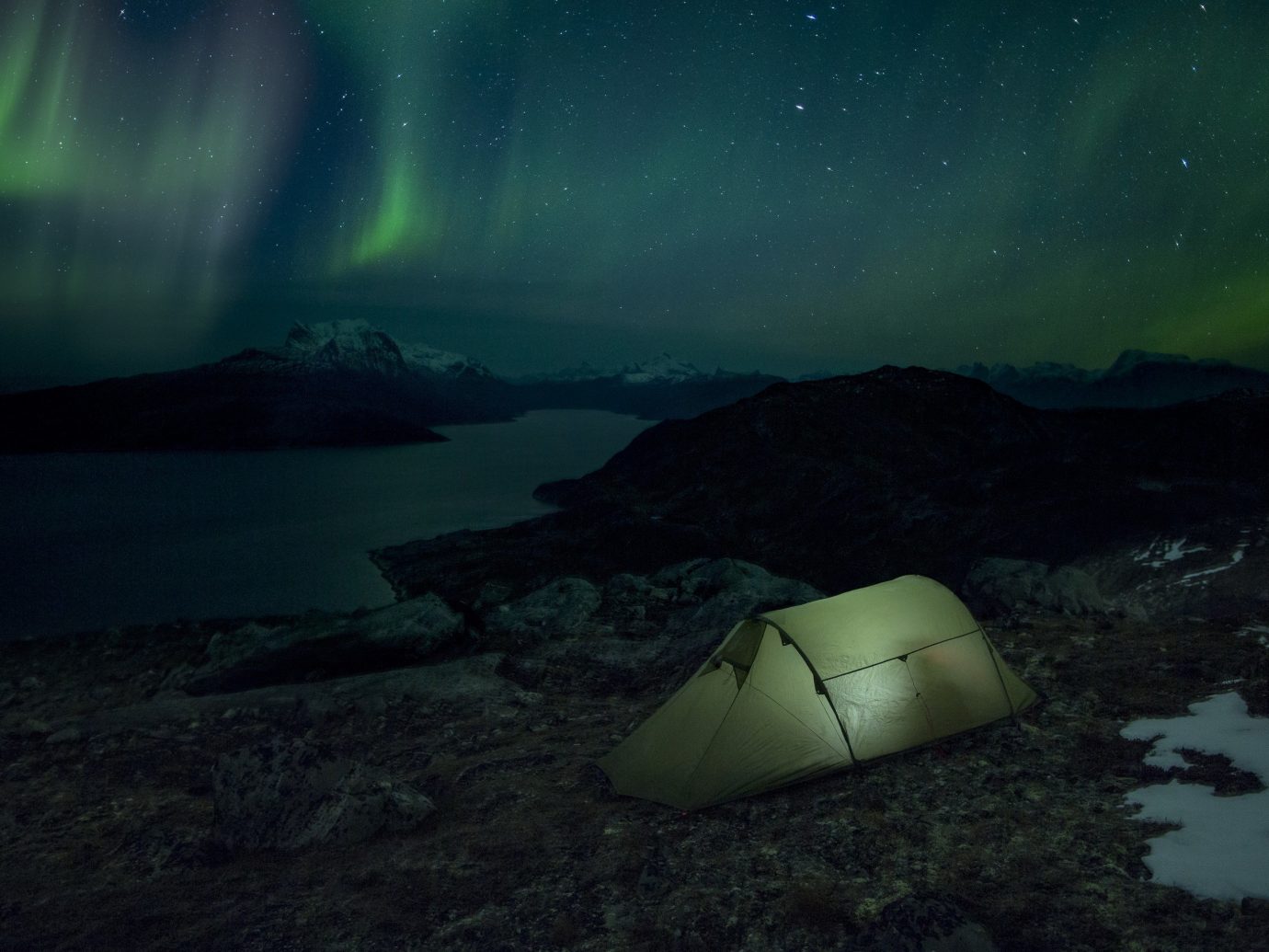 A tent pitched under the Northern Lights with a view of Sermitsiaq Moutain (near Nuuk)