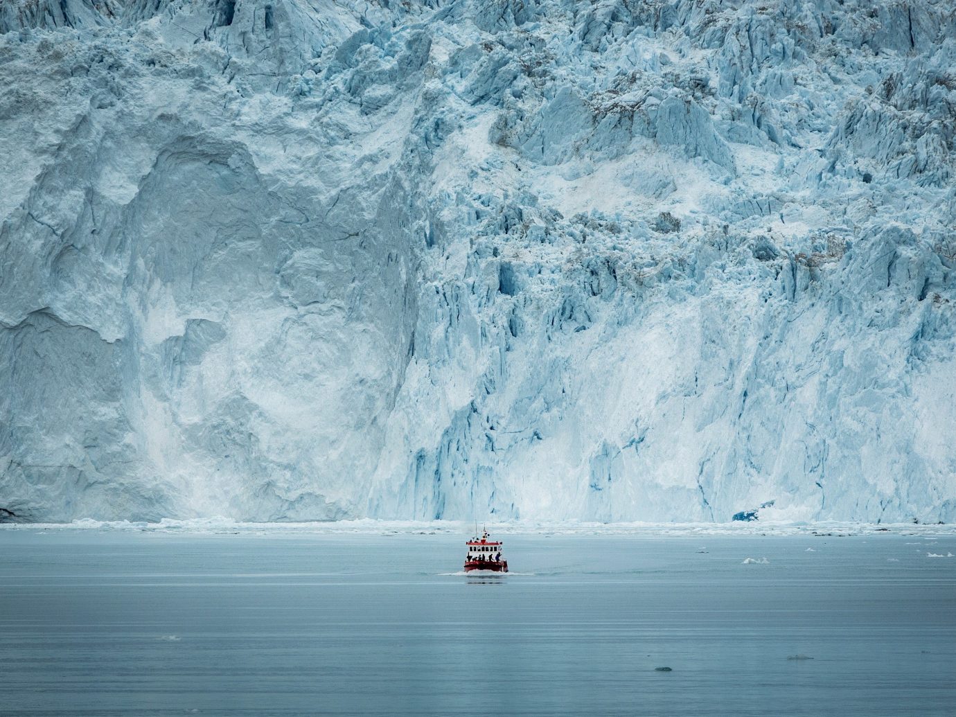 A small passenger boat crosses the Eqip glacier