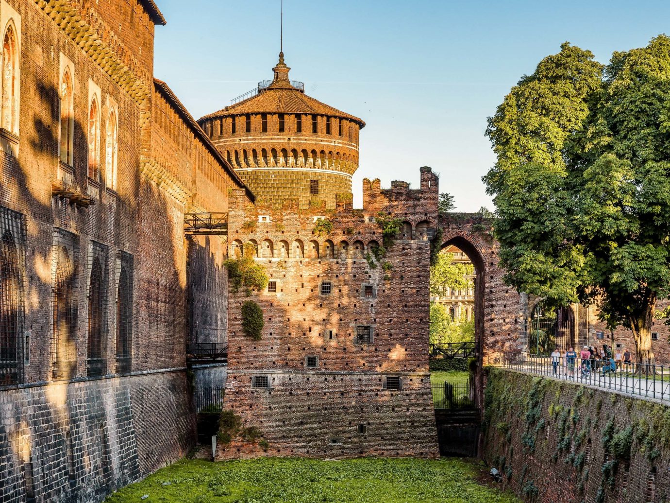 Arts + Culture Italy Milan Nature wall landmark historic site sky medieval architecture château fortification castle Town history tree tourist attraction ancient history stately home building middle ages City facade tourism estate tours palace plant moat arch