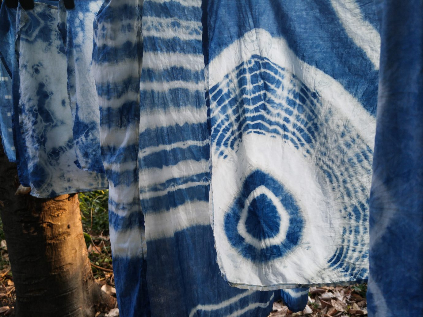 Beautiful natural indigo tie dye fabric with garden view in background.
