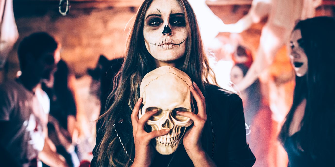 Halloween costume ideas, Young woman with santa-muerte make-up and disguise holding skull at Halloween dungeon party