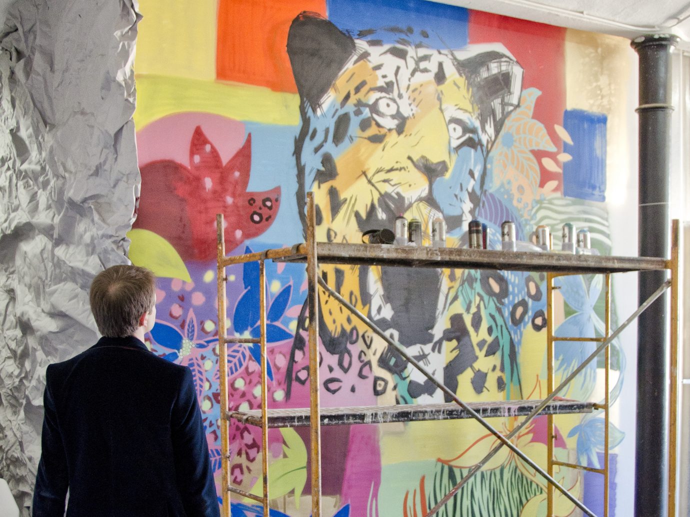 Man in a suit looking at a colorful wall art installation featuring a psychedelic leopard
