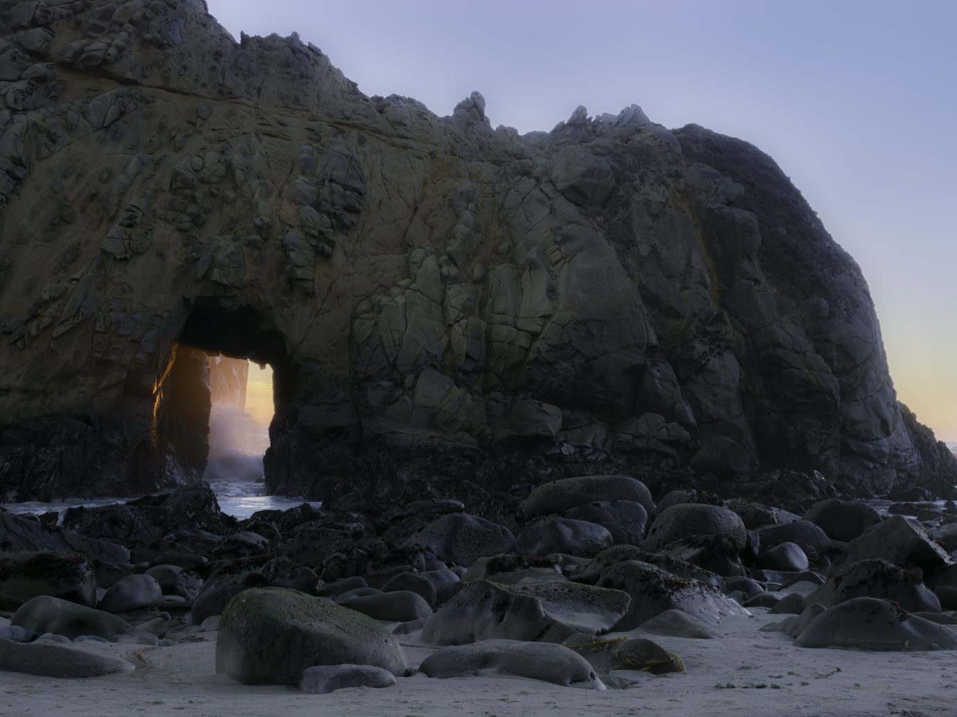 The tide surges through a sunset illuminated sea cave along the Big Sur Coast at Pfeiffer Beach in Los Padres National Forest