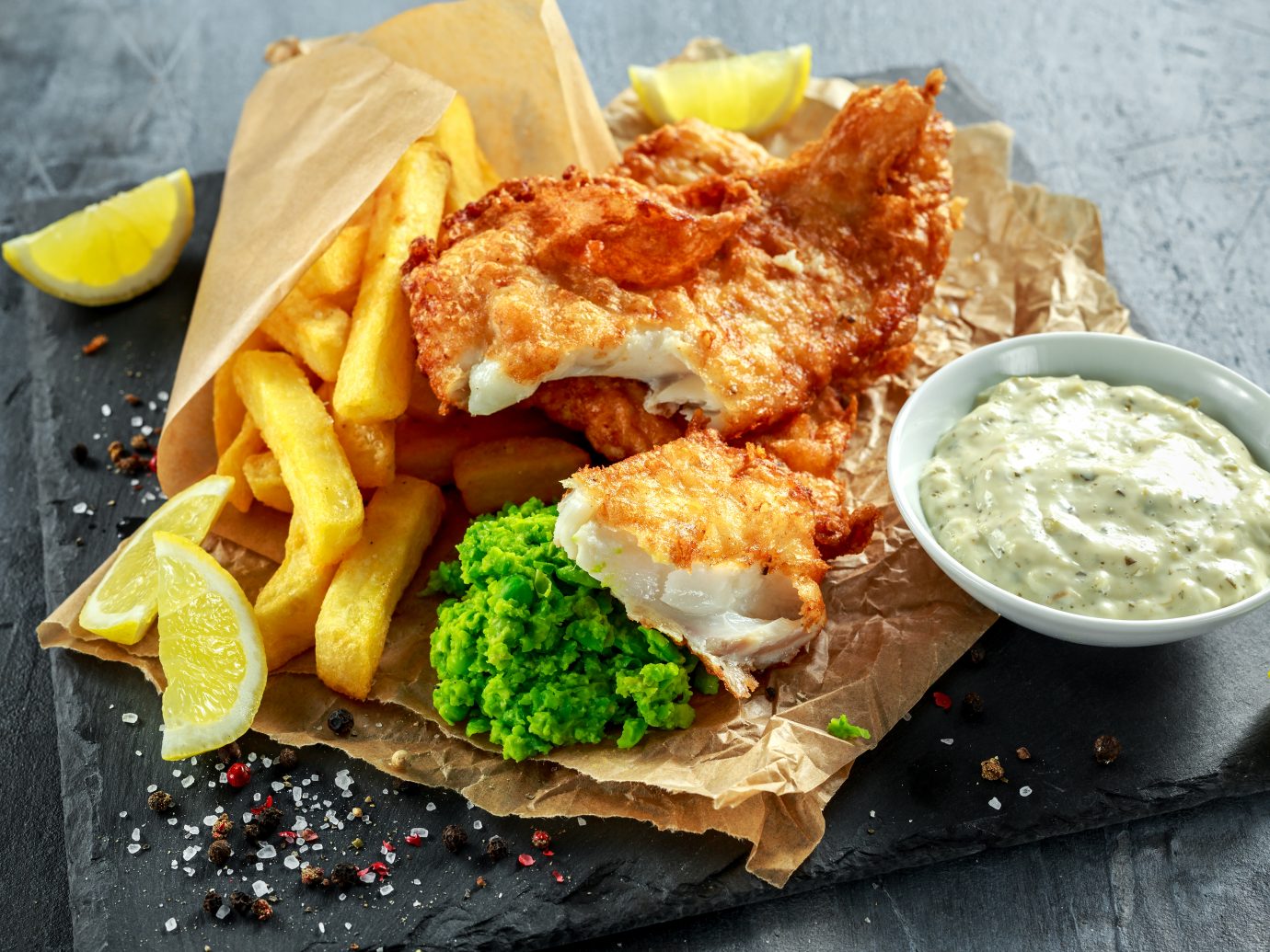 British Traditional Fish and chips with mashed peas, tartar sauce on crumpled paper
