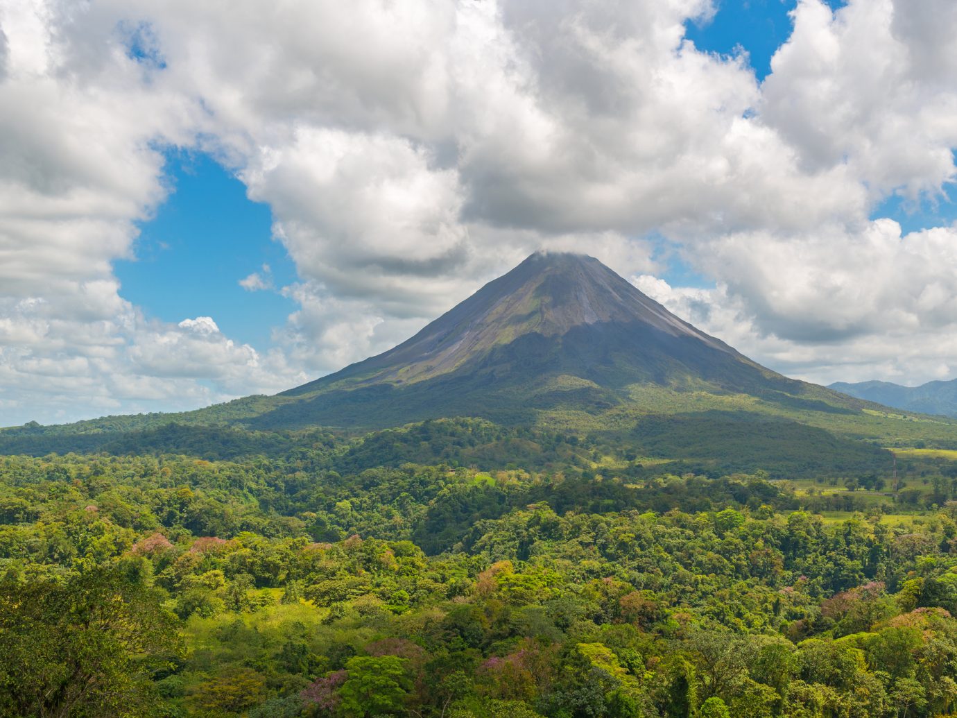 Landscape of the Arenal volcano surrounded by tropical rainforest on a sunny summer day near the cities of La Fortuna and San Jose, Costa Rica, Central America.
