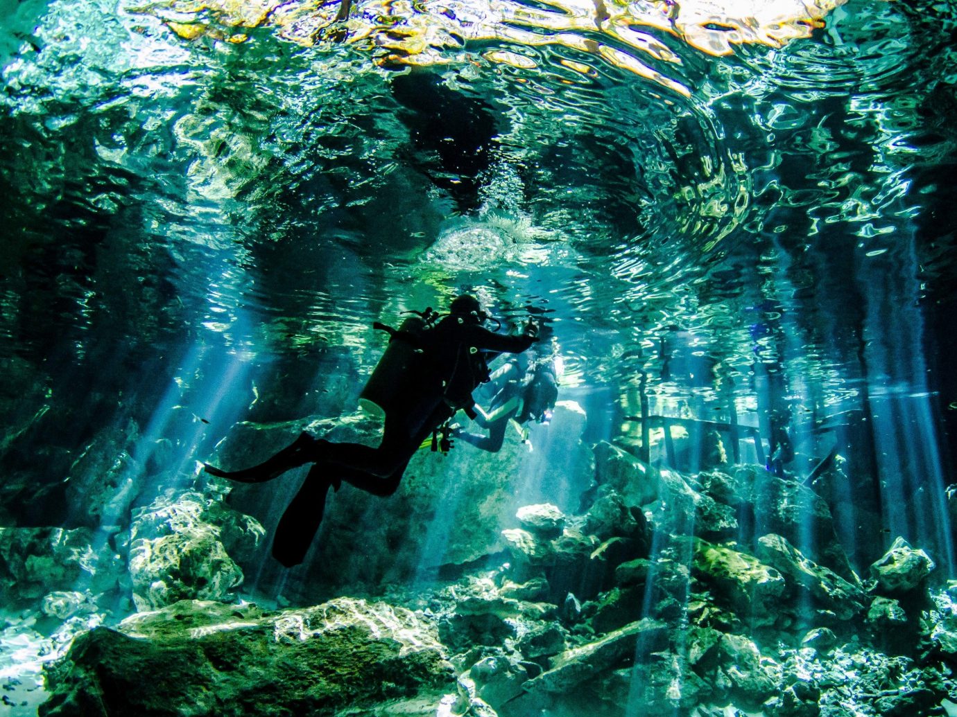 diver in blue waater of a cenote
