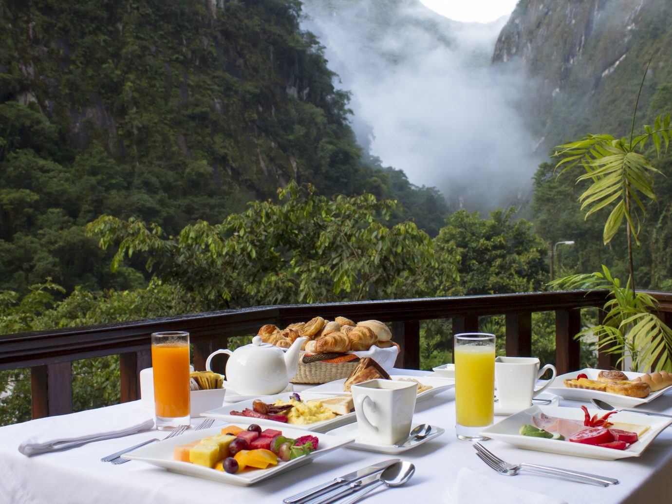 Beautiful breakfast with fruit juices, fruit and pastries overlooking steamy, lush mountains at SUMAQ