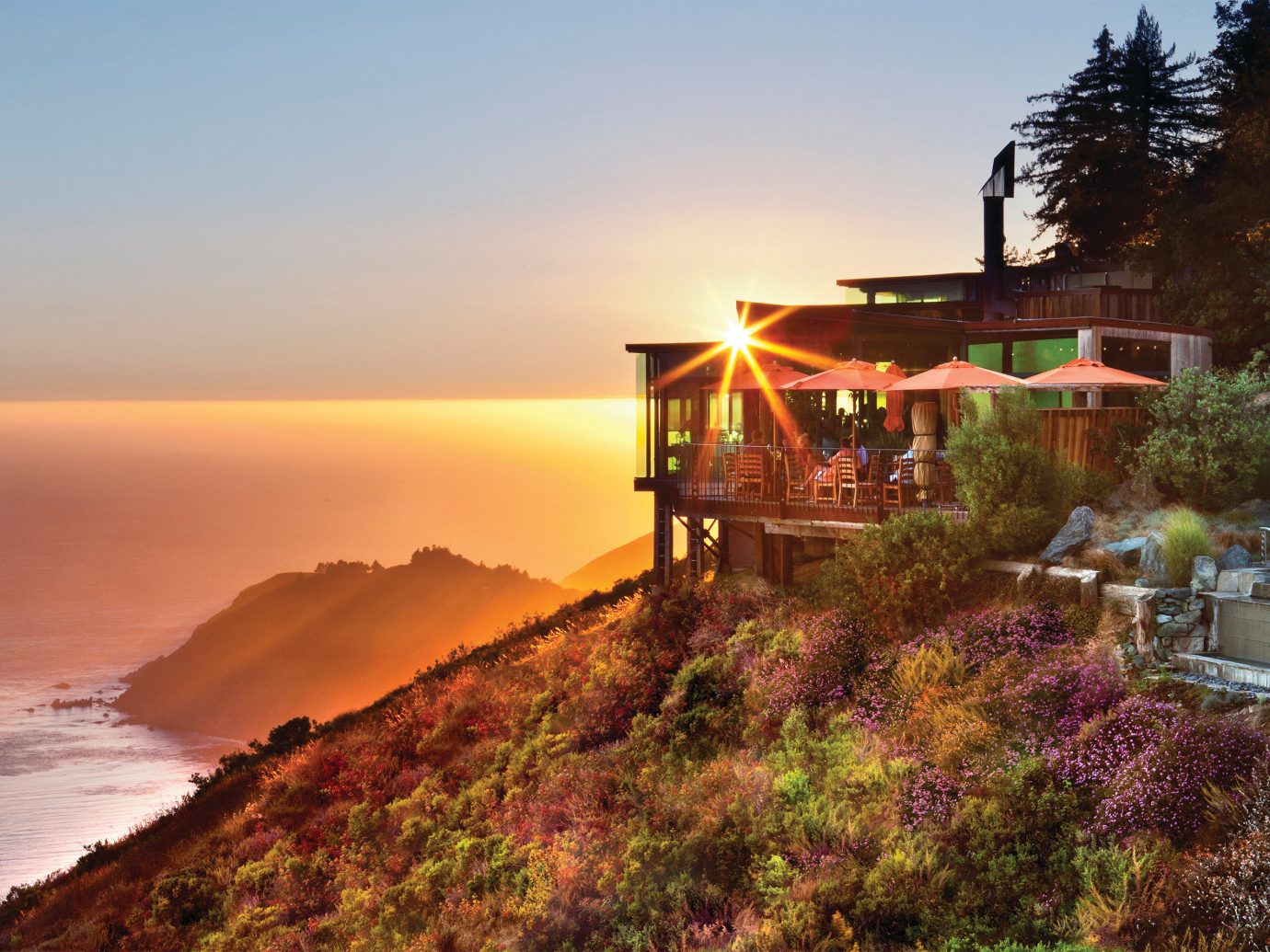 view of Post Ranch Inn perched on a cliff over the ocean during sunset