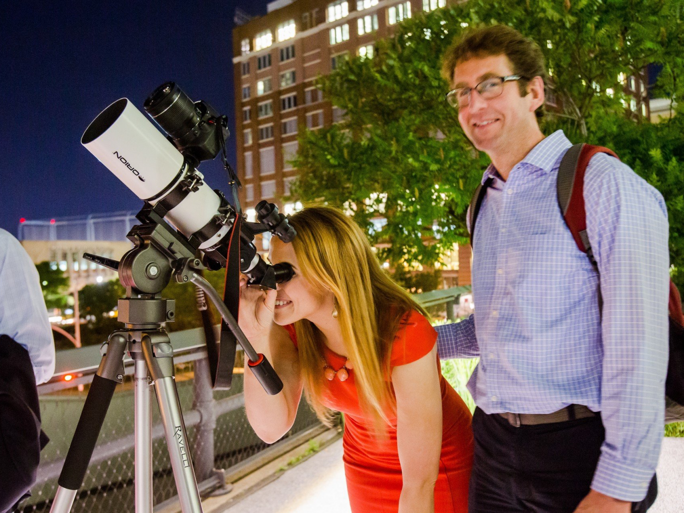 A man and woman using a telescope at night at The High Line in NYC