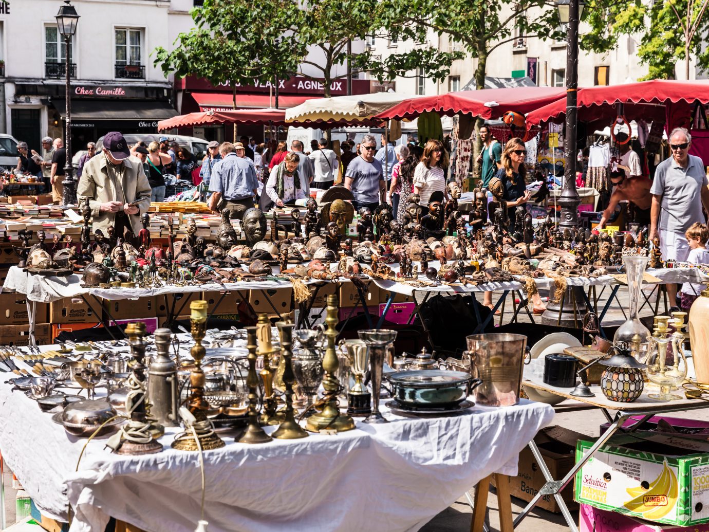 People choosing rare and used books, wooden masks and figures of African culture at the historic flea Aligre Market (Marche d'Aligre) in the Bastille district.