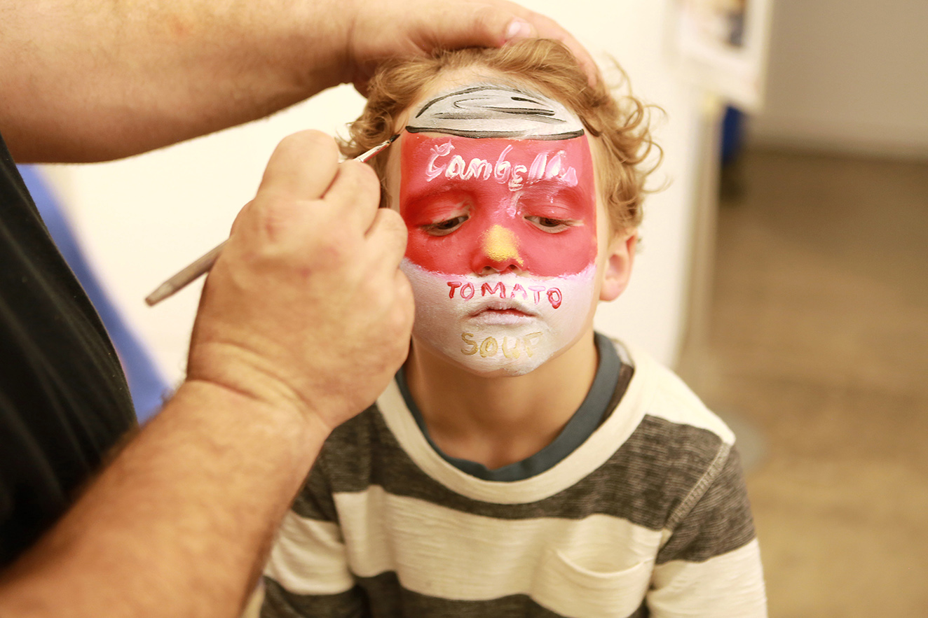 kid getting faced painted with Campbell's soup logo
