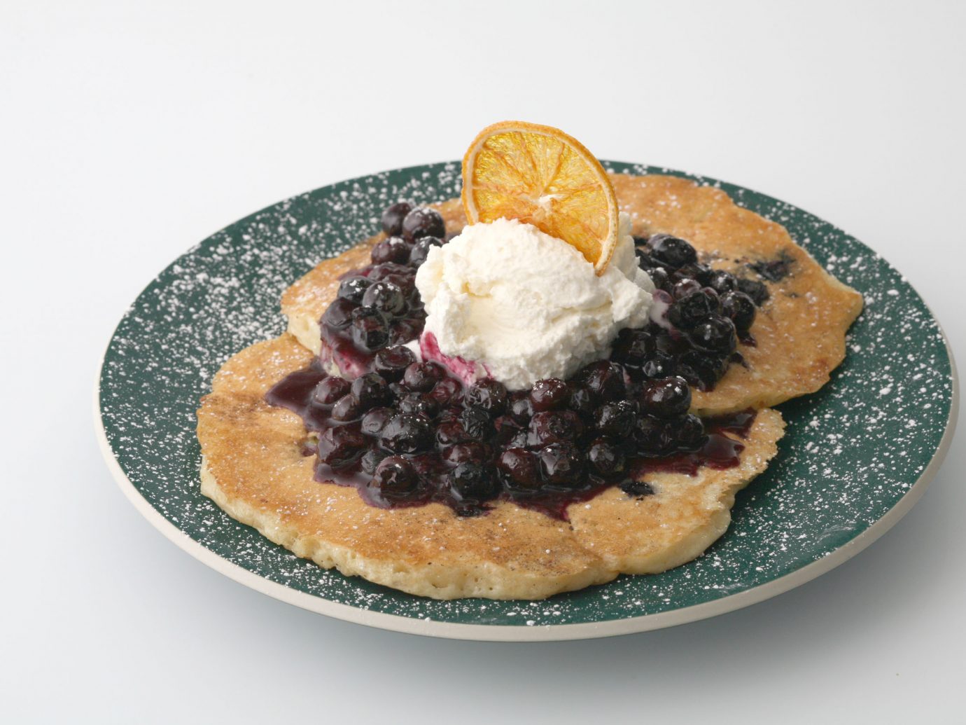 Blueberry pancakes with whipped cream and orange slice