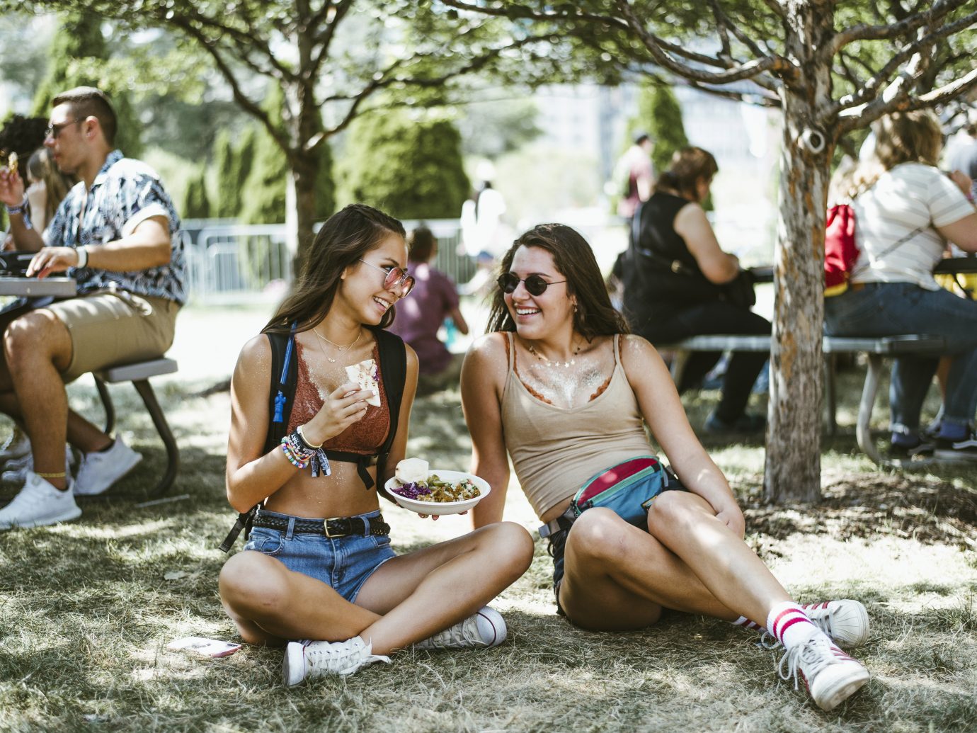 two girls eating falafel on the grass