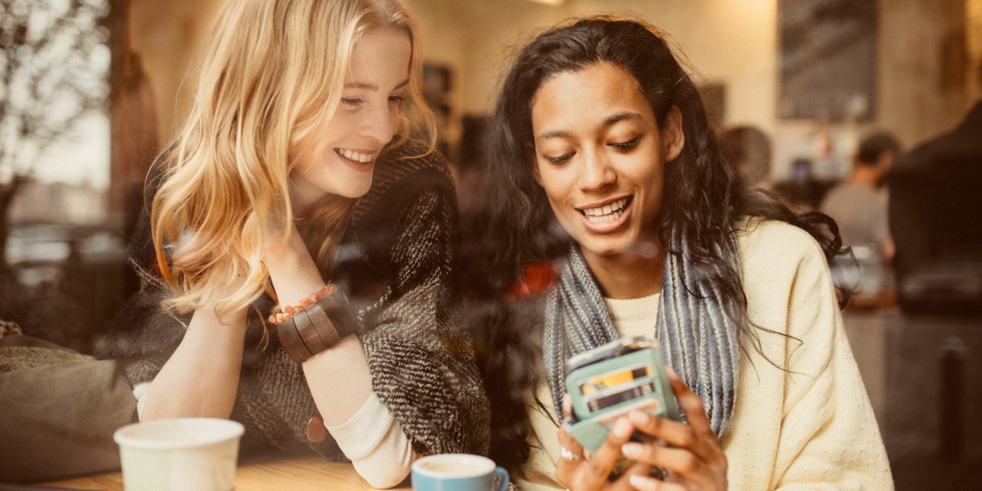 Girlfriends using Smartphone in Coffeeshop to shop online