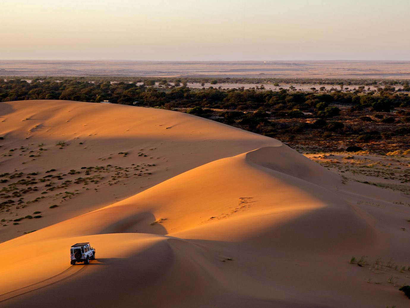 A car is driving through sand dunes
