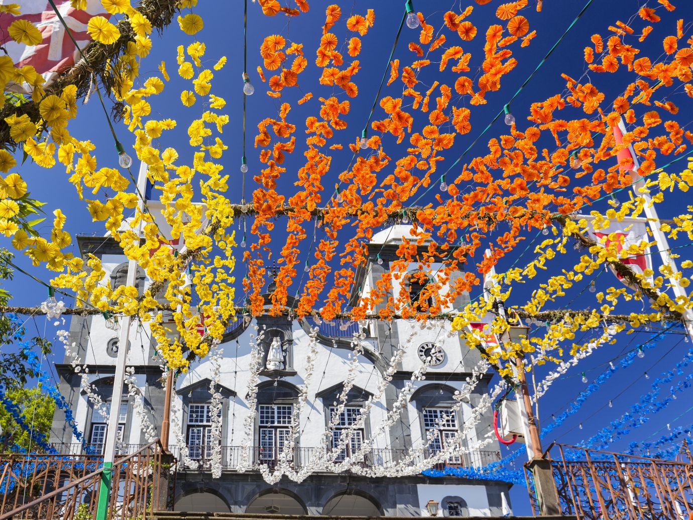 Decorate yellow, orange, blue and white flowers strung up leading to the Church of our Lady of Monte in Funchal, Portugal.