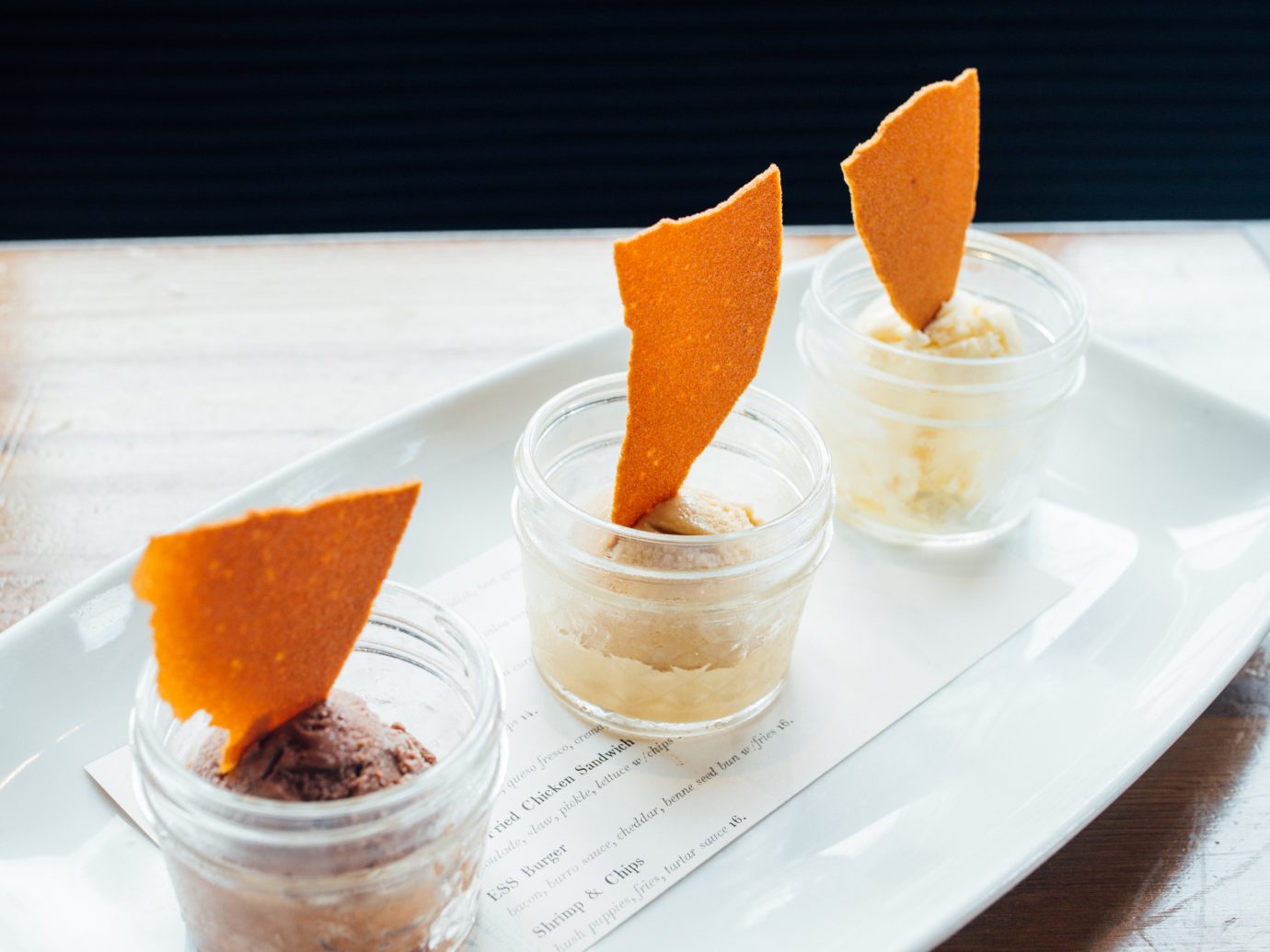 Three ice creams in tiny mason jars with a tortilla chip sticking out of each