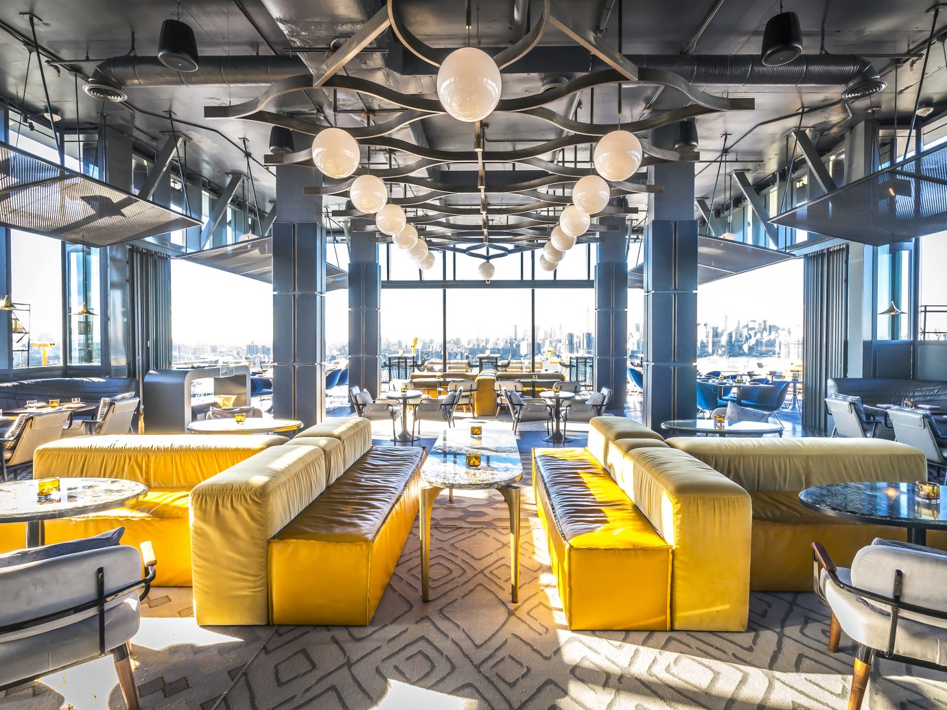 sunny day showing off interior of a bar with bright yellow couches and a very airy space