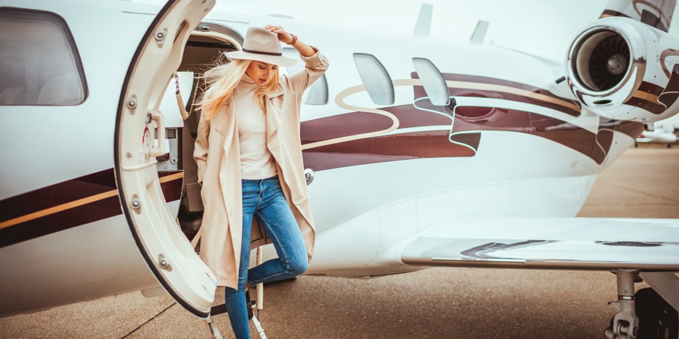 how to look stylish at the airport. Stylish woman watching her step as she's disembarking from a private airplane parked on an airport taxiway.