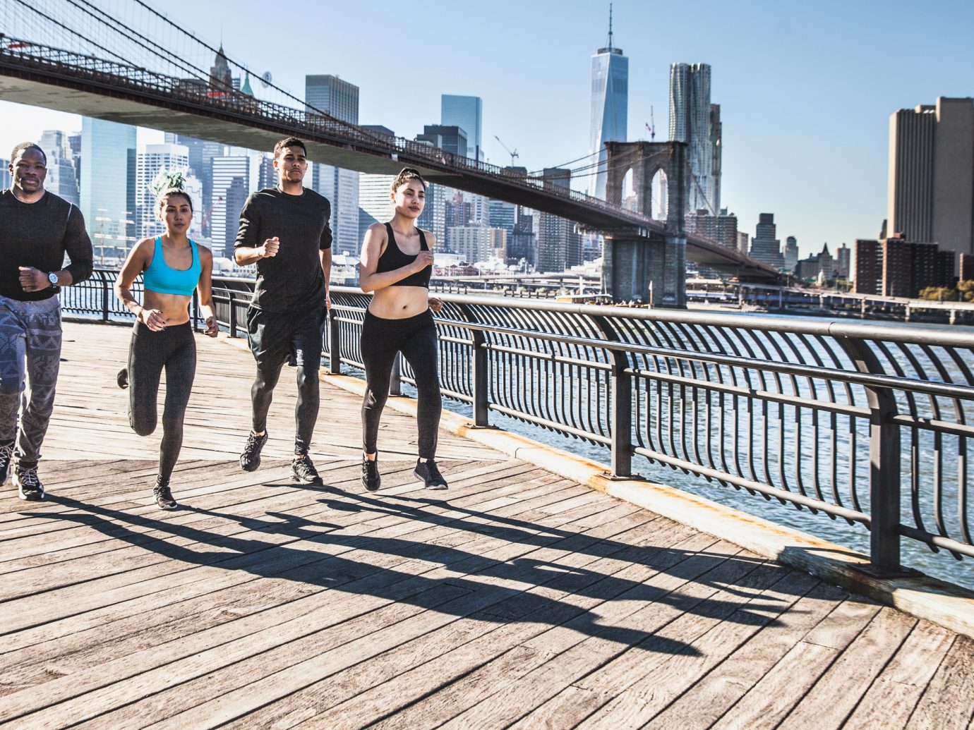 Group of healthy mixed race people running in DUMBO - New York City - USA. They are running in the city streets wearing professional sport clothes.