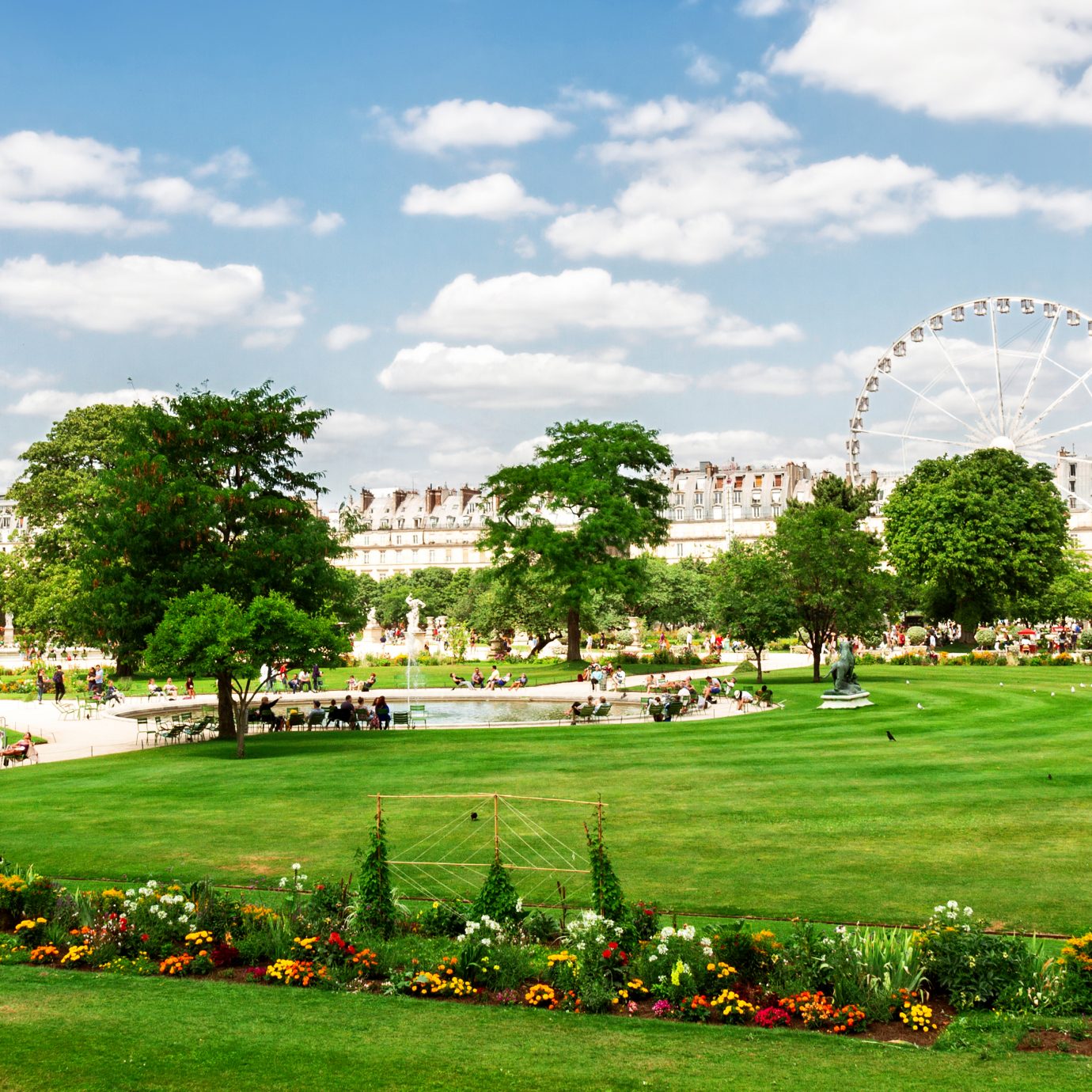 Tuileries garden at summer day, green lawn and blue sky with clouds, Paris France