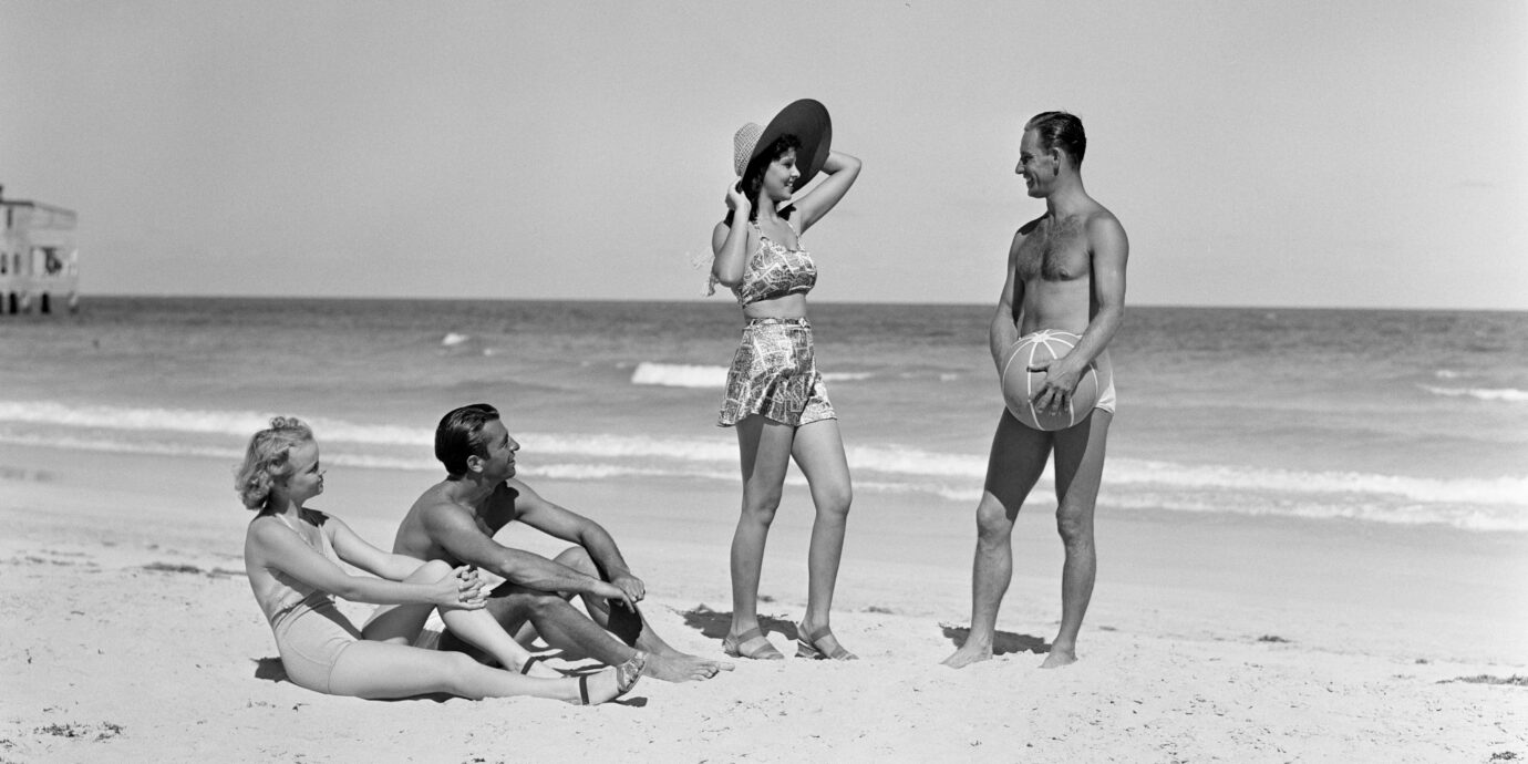 UNITED STATES - CIRCA 1930s: Two couples standing on beach.