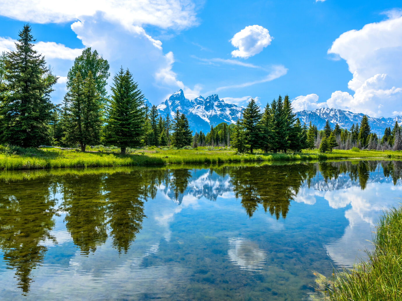 A panoramic spring view of clear and calm Snake River flowing at base of Teton Range in Grand Teton National Park, Wyoming, USA.