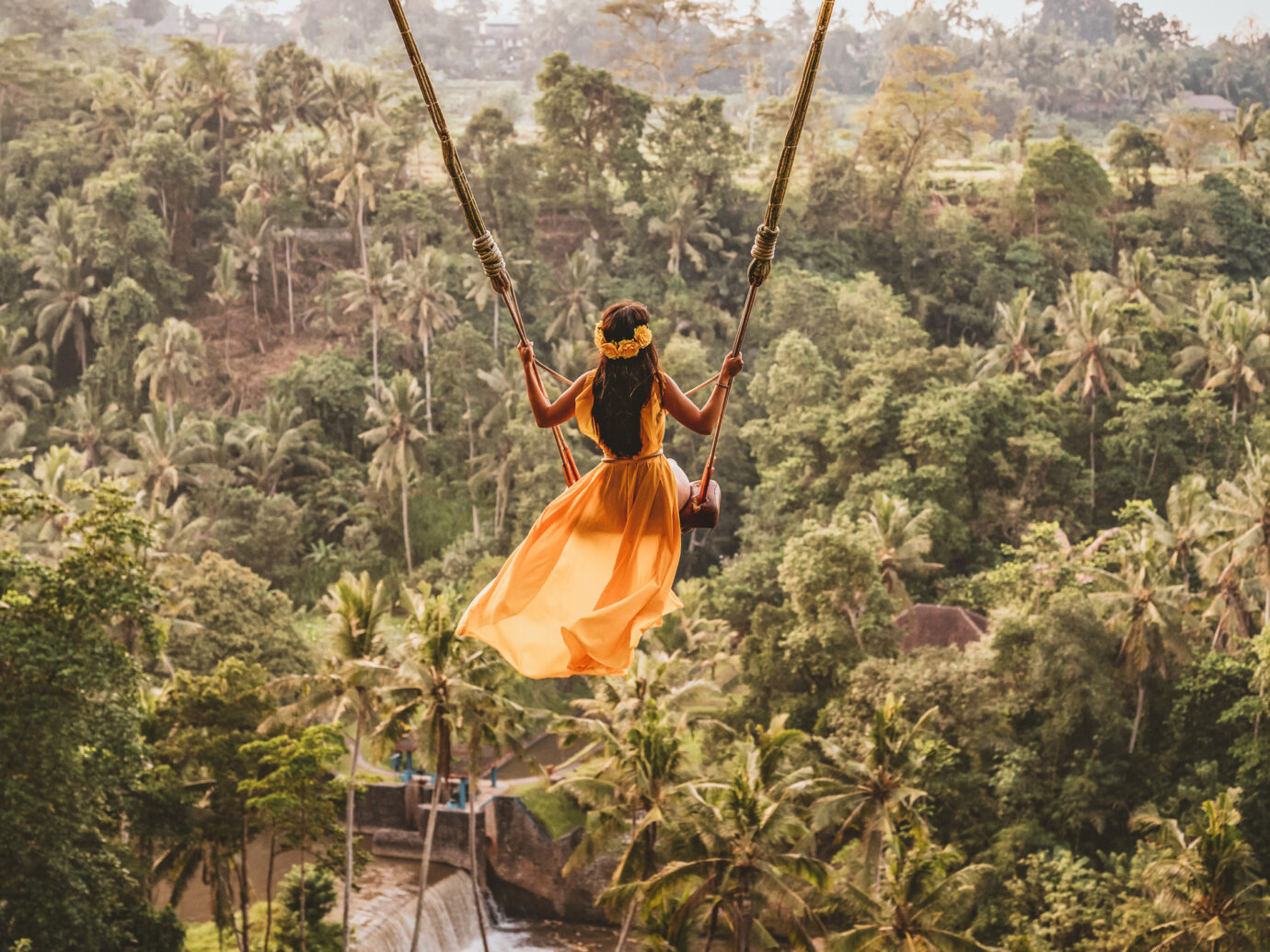 Photo of woman with long swing and forest view. Young woman swinging in the jungle rainforest of Bali island, Indonesia