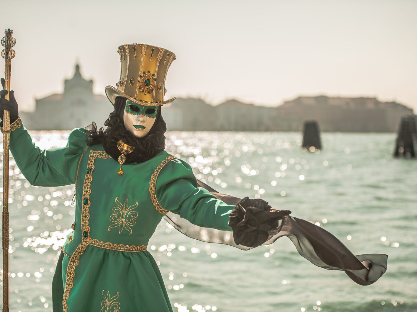 Masked Person in Green Carnival Costume with Golden Hat Posing near Canale Grande, Venice
