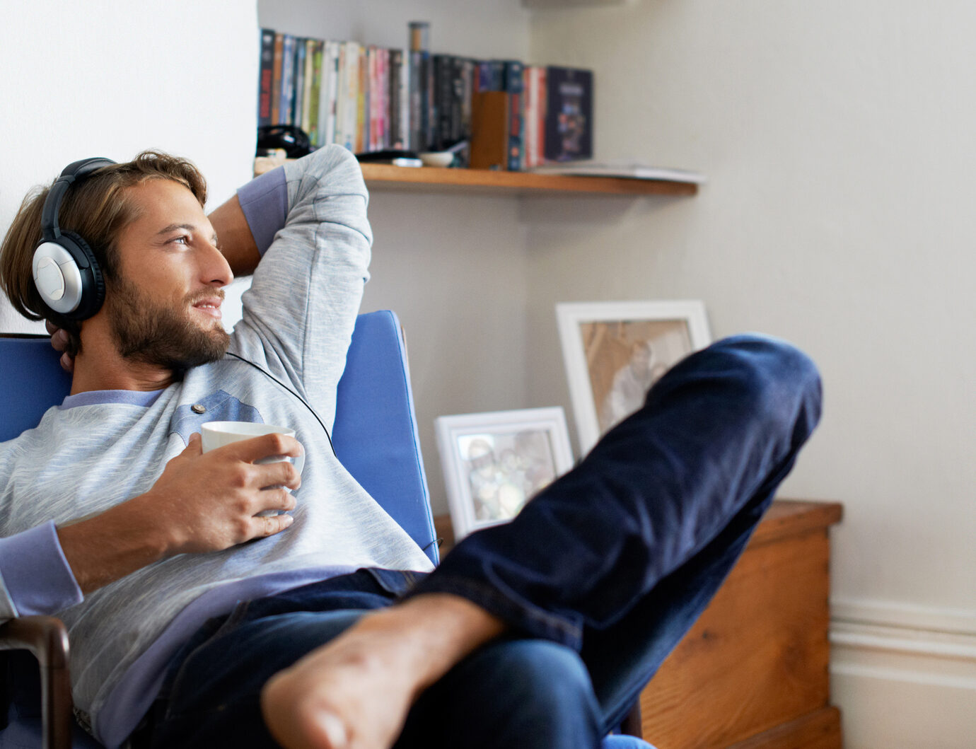 Shot of a young man having coffee while listening to music at home.
